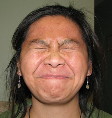 an older asian woman smiling while looking at the camera