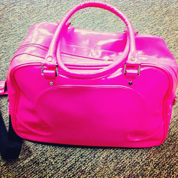 a bright pink duffel bag sitting on the carpet
