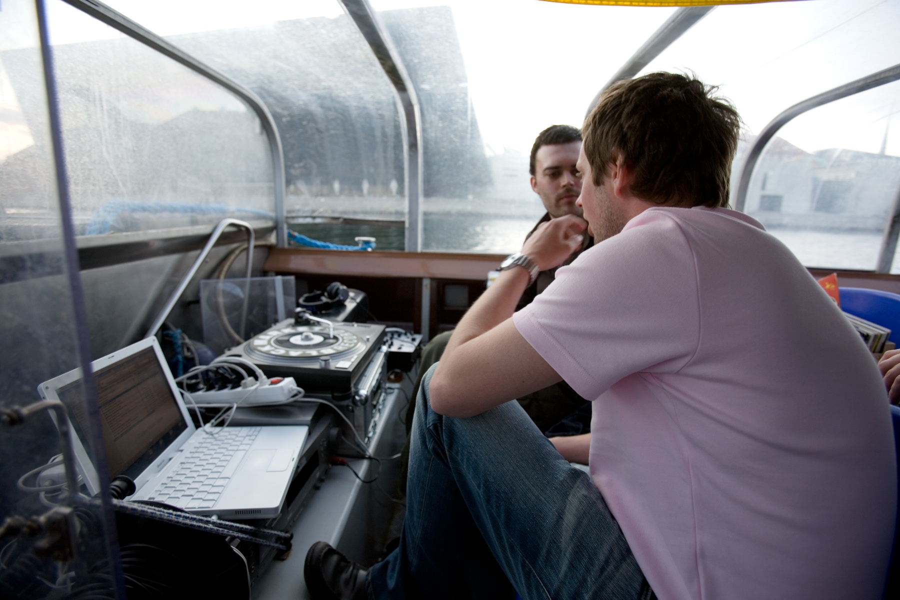 two men sitting down with laptops on a boat