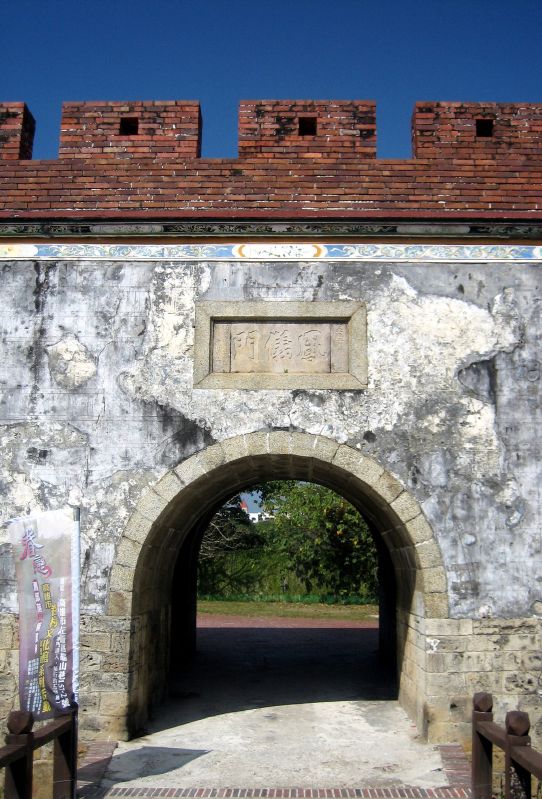 an old stone gate with a brick roof on top