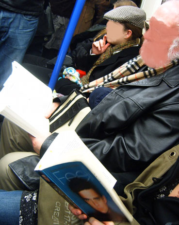 a man is sitting reading while people are seated down
