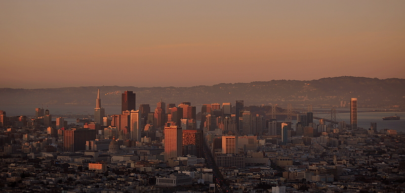 a city is at dusk seen from atop a hill