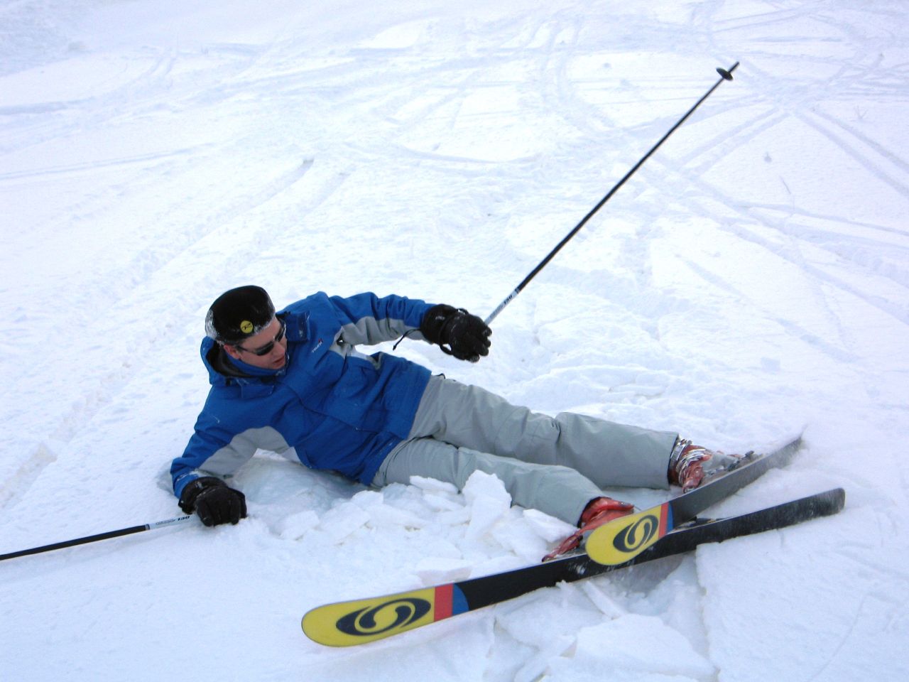 a man skis and is falling down in the snow