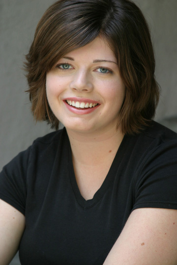 a young woman smiling and sitting in front of a wall