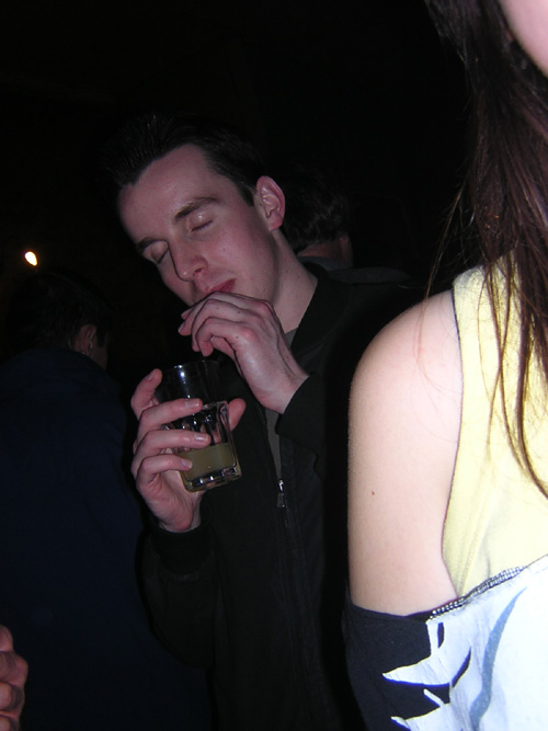 a man is drinking from a glass in a crowd