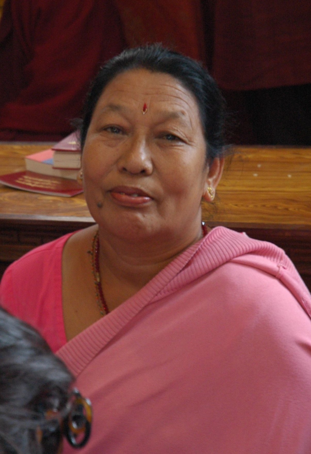 a woman with a pink shawl stares into the camera