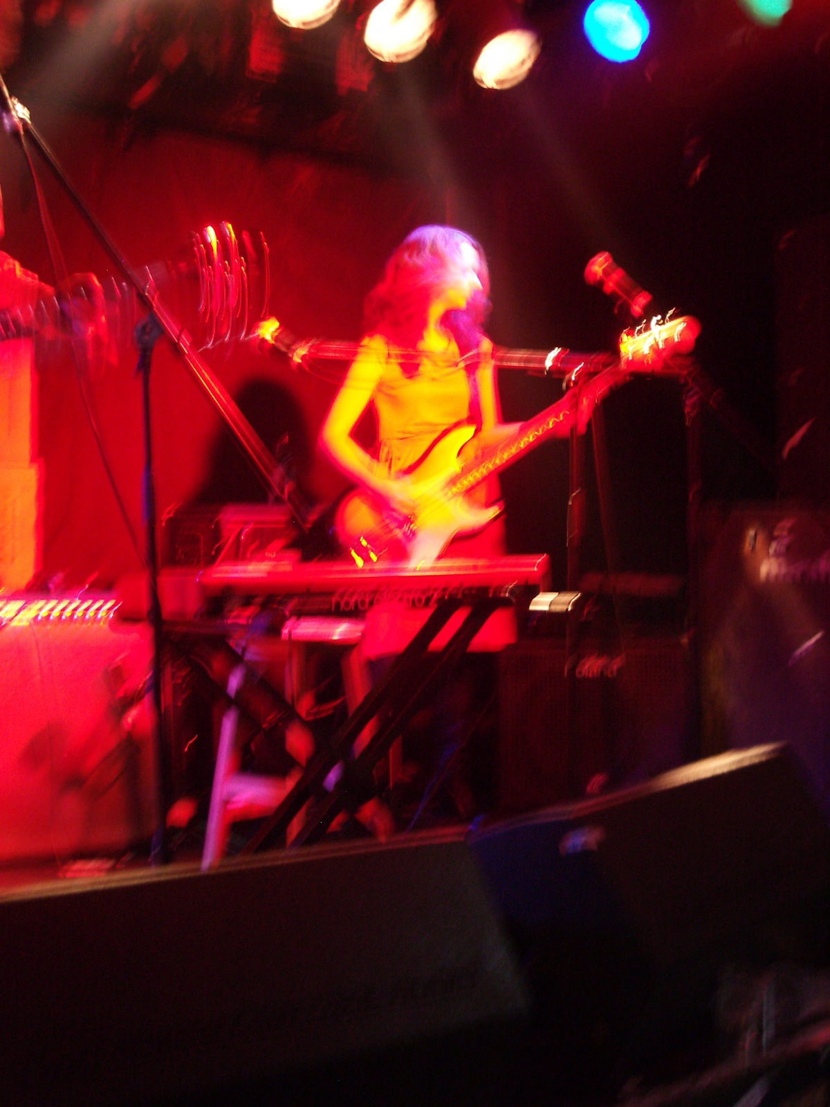 a woman in yellow is playing guitar on stage