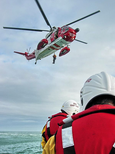 a helicopter hovers over some water near a group of workers