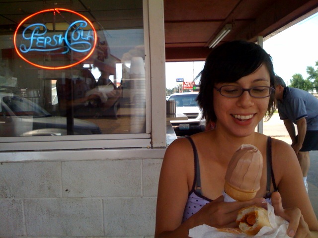 a woman is smiling as she eats a doughnut