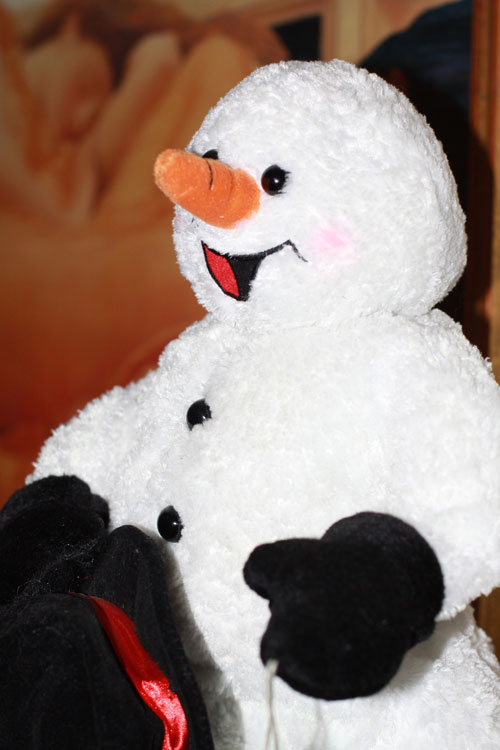 a snowman doll has a red nose and black ears