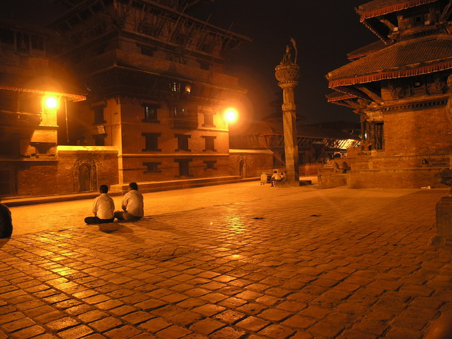 two people are sitting on the ground at night