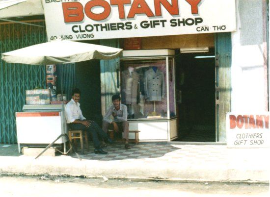 two men sit in front of a clothing shop