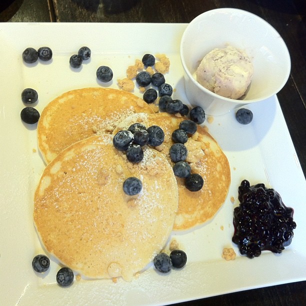 pancakes sitting on top of a white plate covered in blueberries