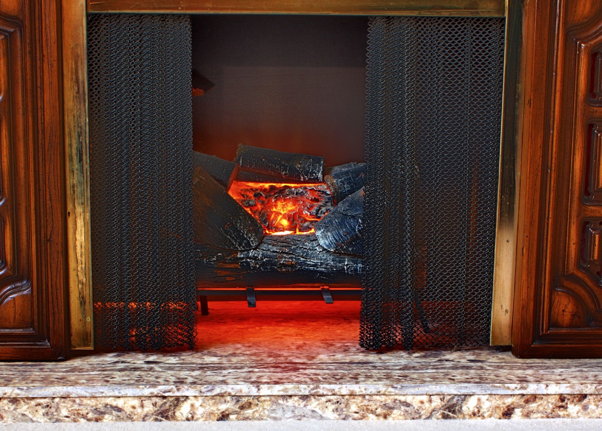 a fireplace is lit with red fire and lots of black mesh