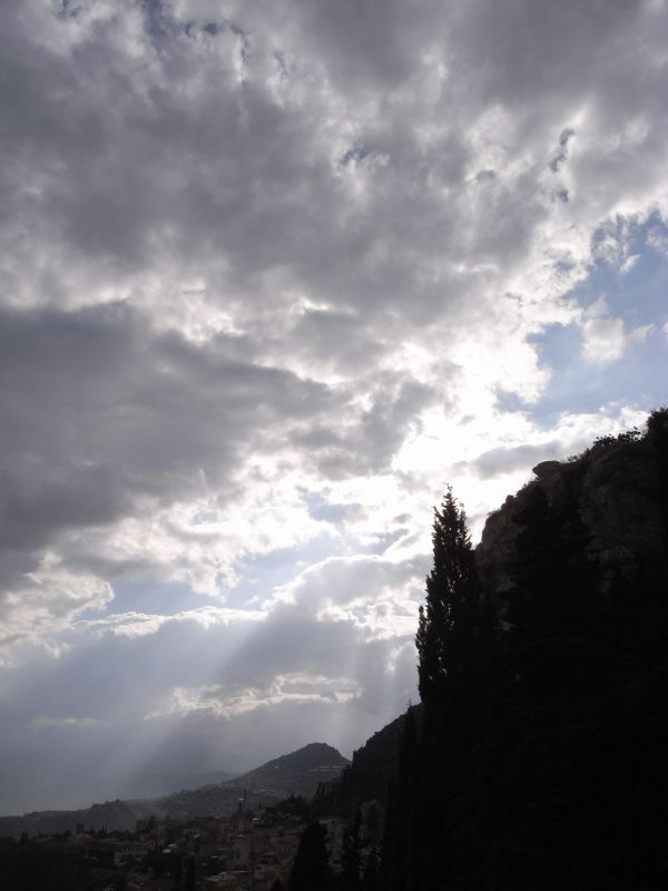 the sun shining through the clouds over a village