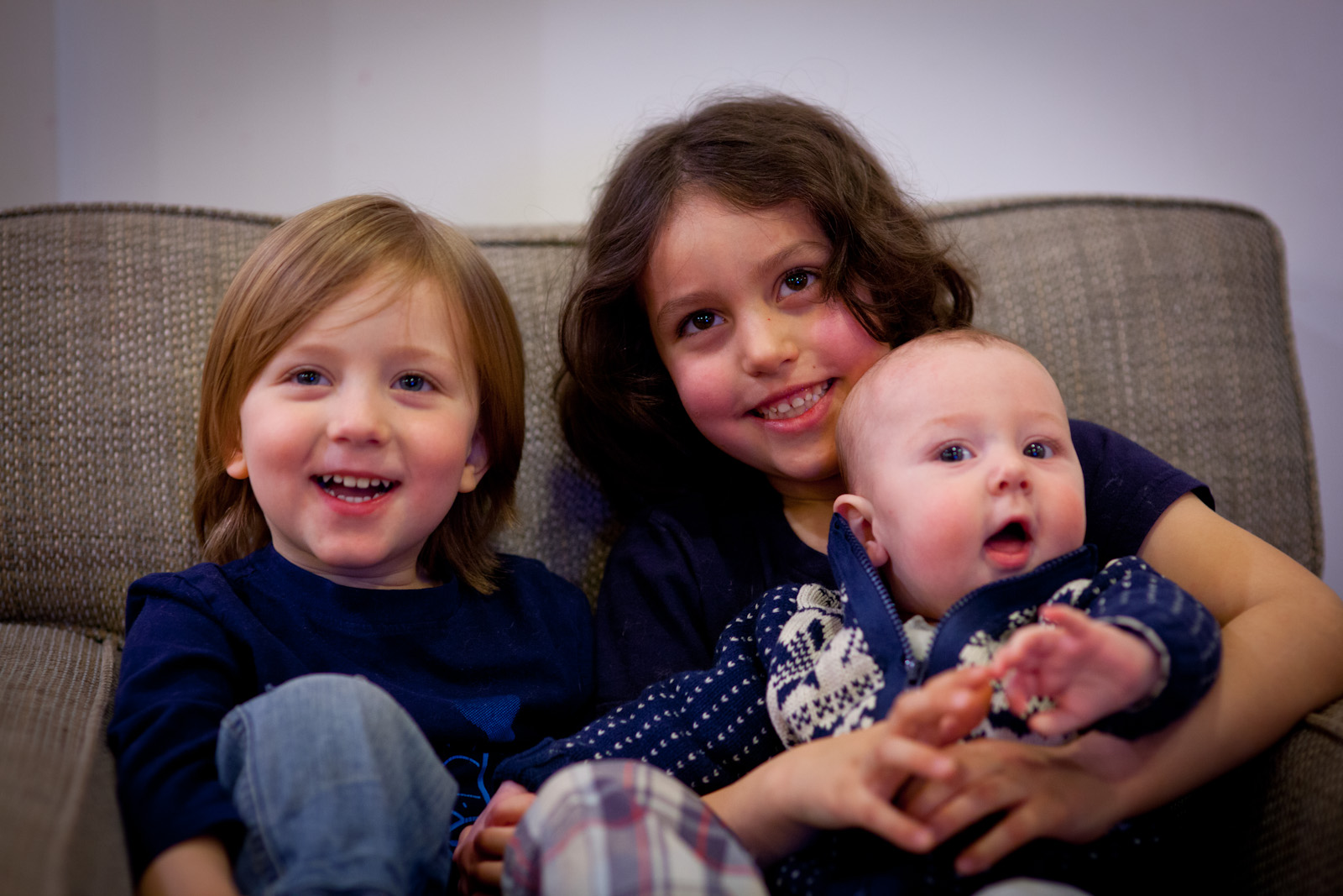 three girls are sitting on the couch with their babies