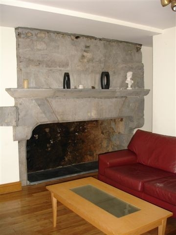 a couch and table sitting in front of a stone fireplace