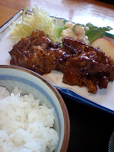 a dinner plate with a meat, rice and an apple