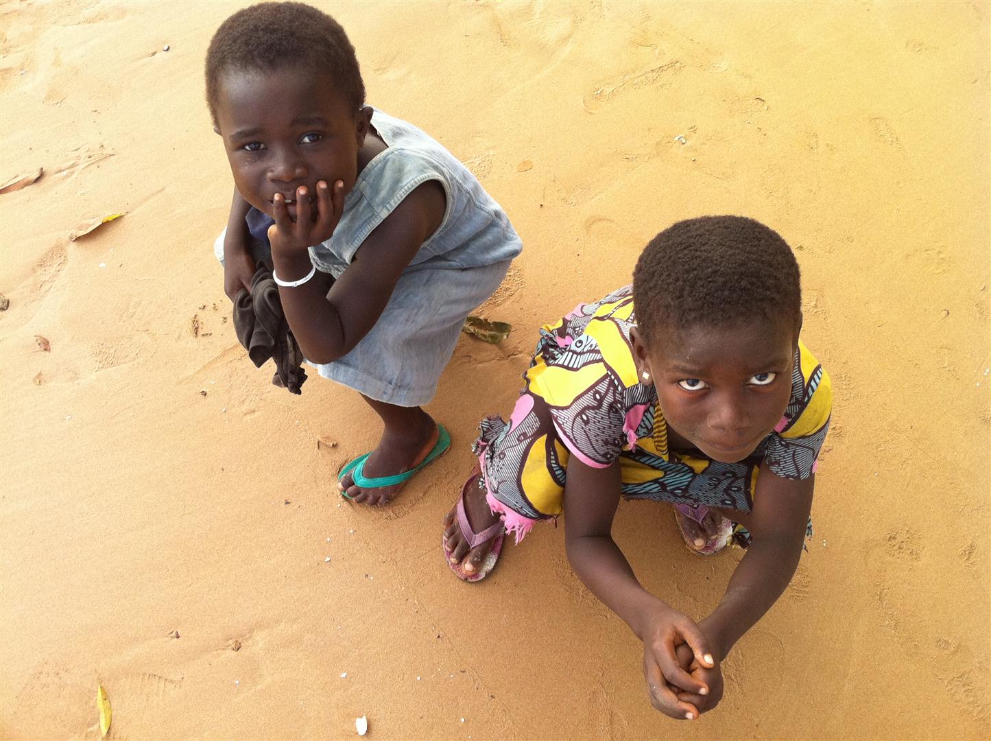 two small children sitting on the ground with shoes on