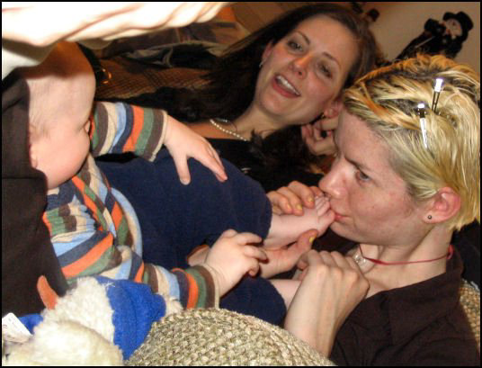 a woman holding a baby while two other people sit behind her