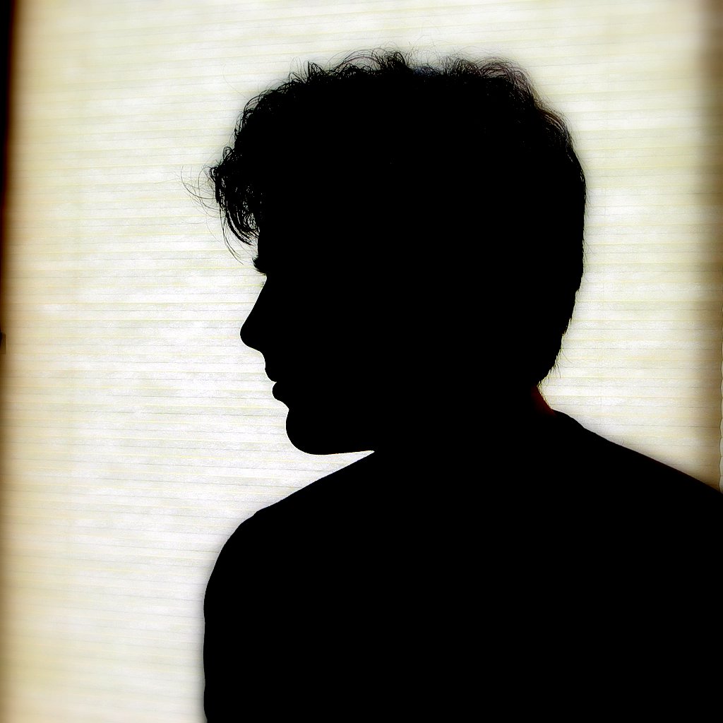 silhouette of the head and shoulders of a man, with light in the window