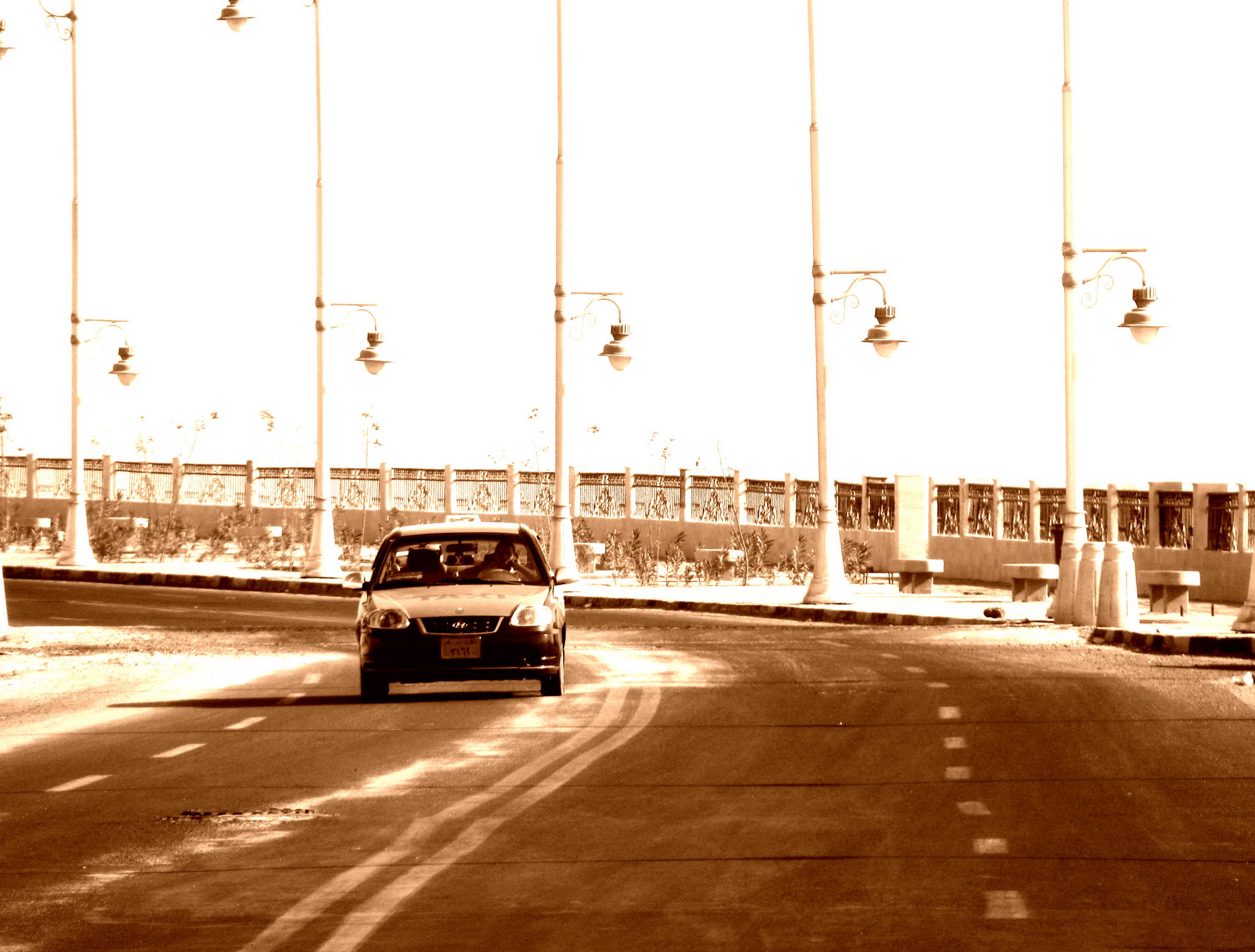 car moving along an empty road in front of some poles