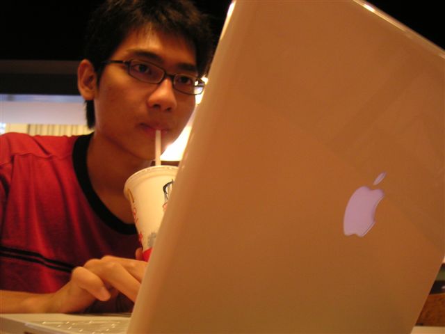 a man drinking a drink next to an apple laptop computer
