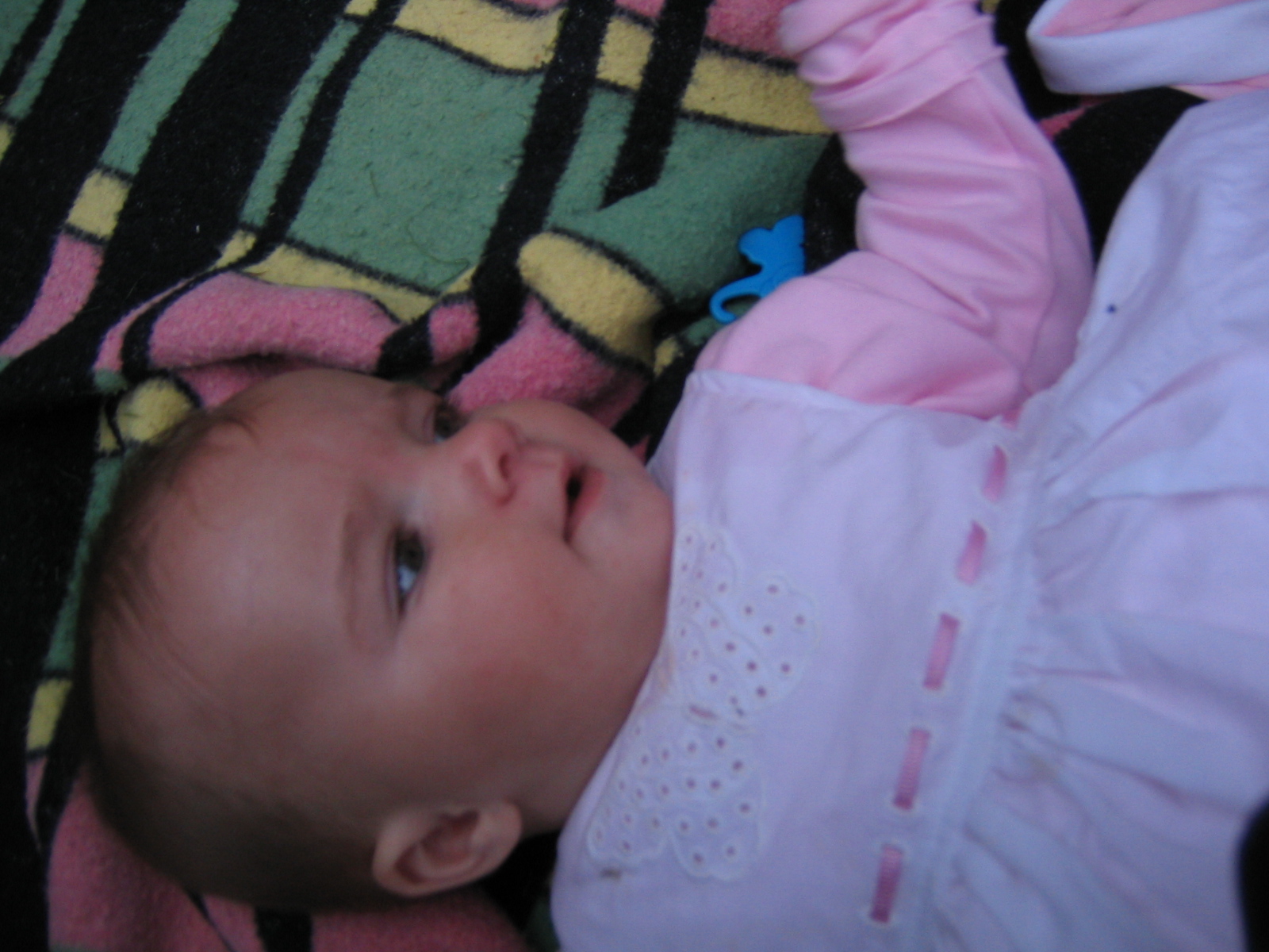 an infant lays on her side looking up at soing