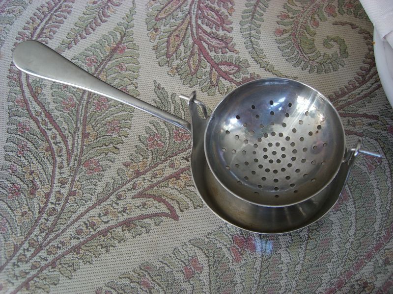 a metal strainer sitting on a floral patterned fabric