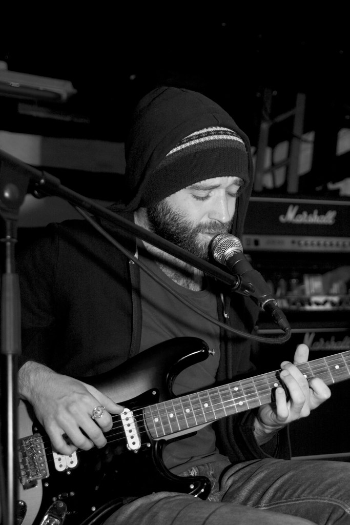 a man that is playing the guitar in front of a microphone