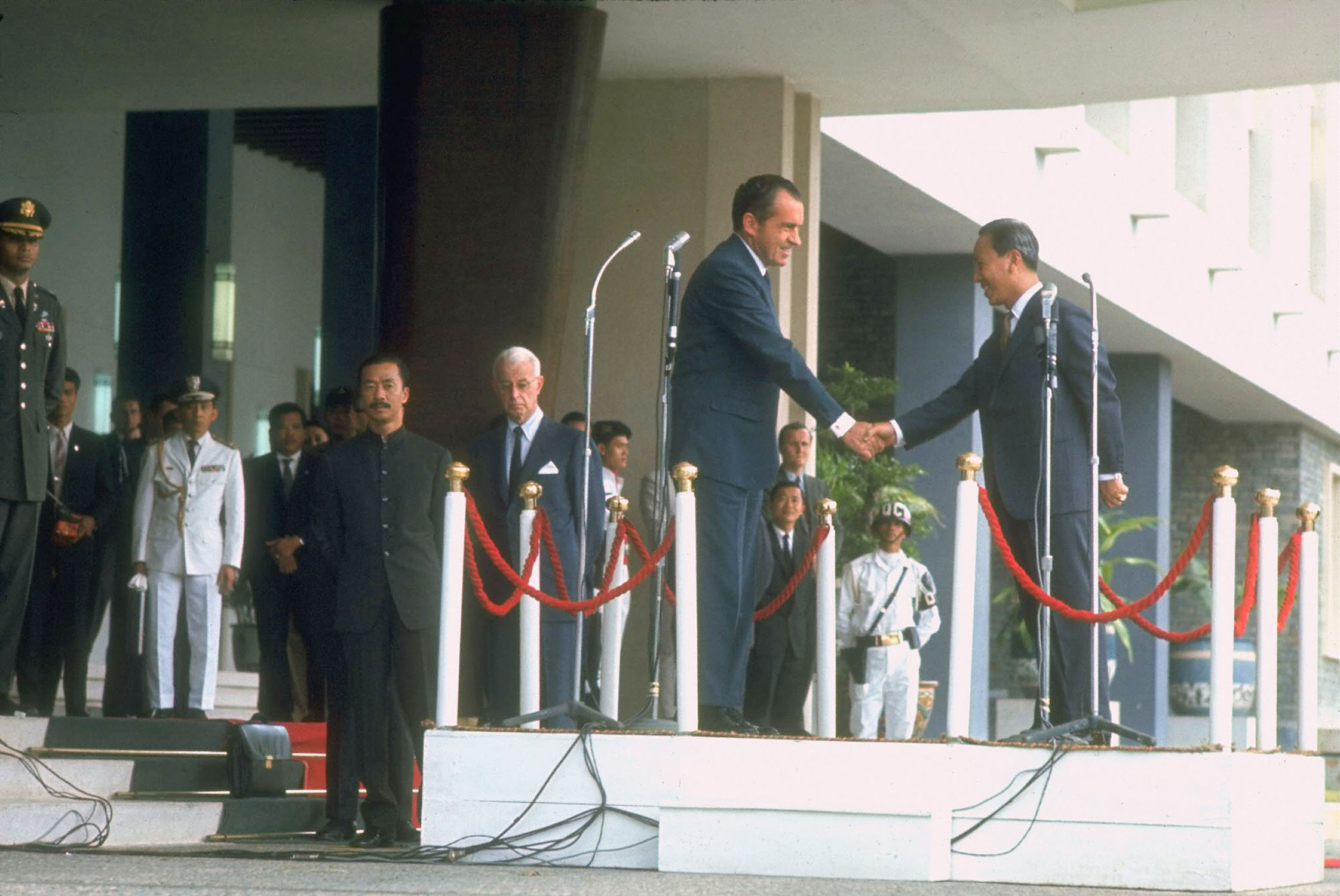 two men in suits and ties shaking hands at a ceremony