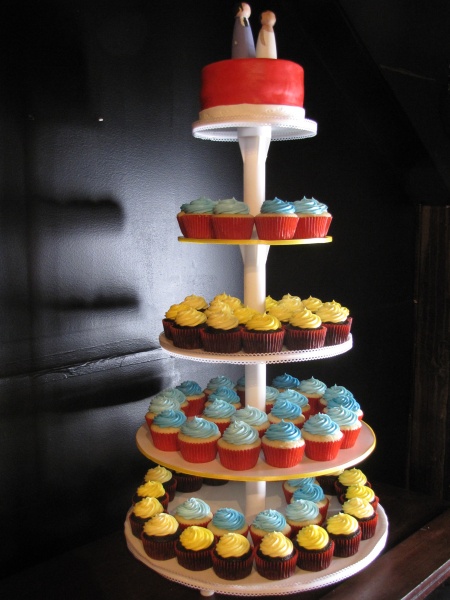 three tiered cake with cupcakes on top