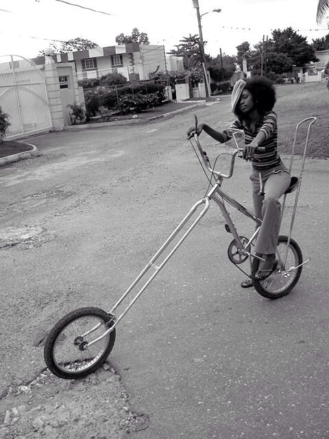a girl rides a tiny metal tricycle down the street