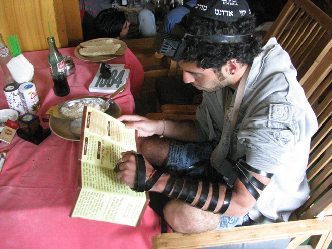 a man sits reading a menu with a man sitting beside him in a chair