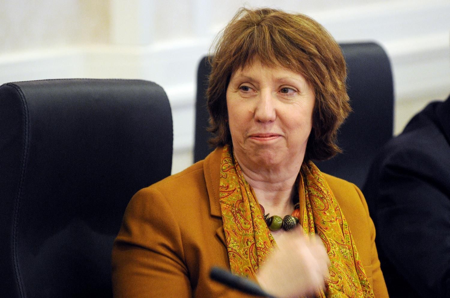 a woman with brown hair sitting in a black chair and gesturing at someone