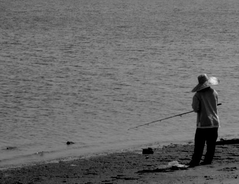 a man is standing on the shore of a lake fishing