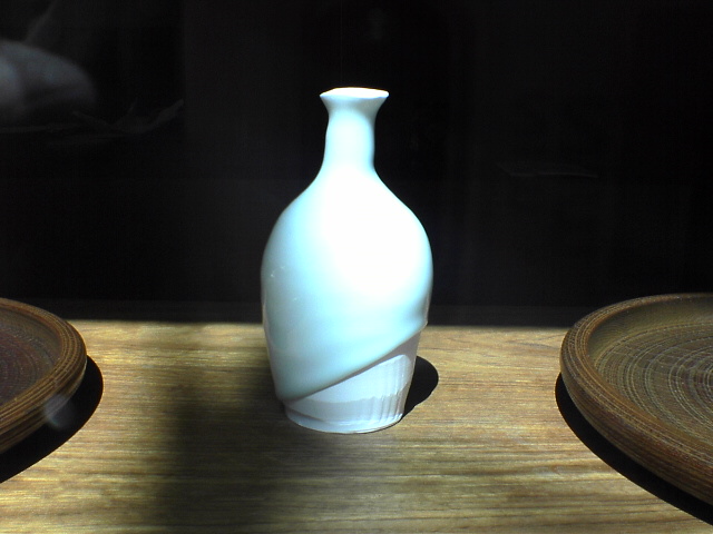 a small white vase with a round wooden base