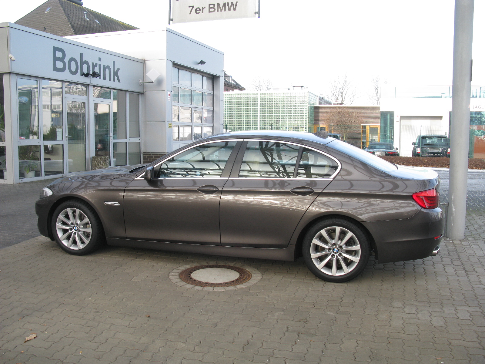 a brown car parked outside of a bmw showroom