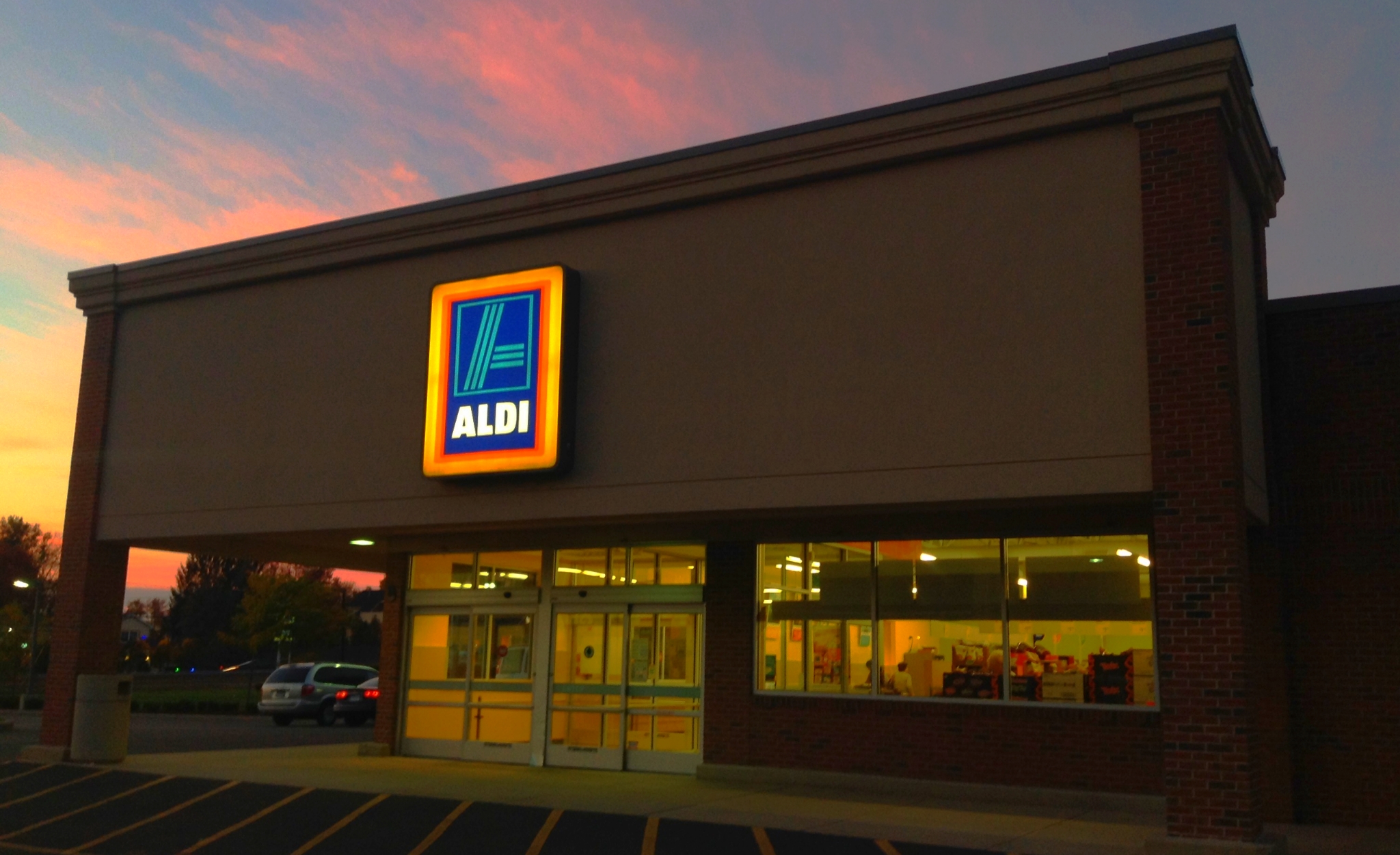 the sun sets over a store front and cars outside