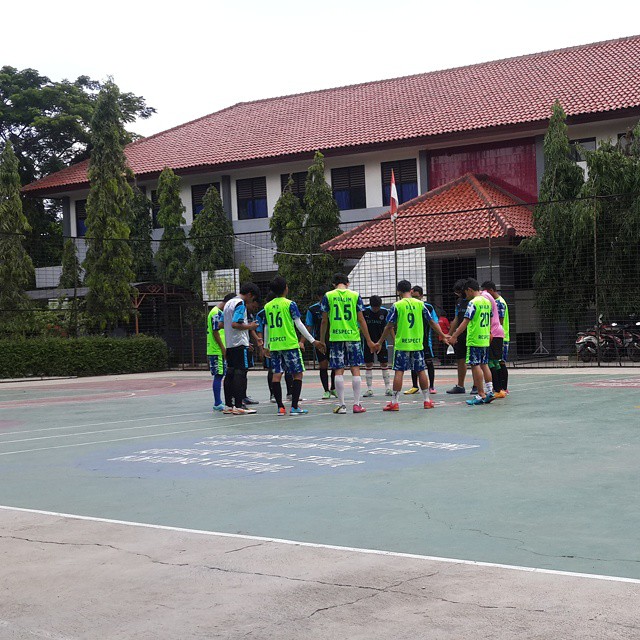 there are many s wearing green vests playing volleyball on a court