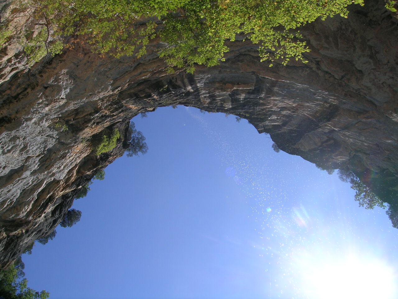 a sunny blue sky behind a natural archway made of rocks