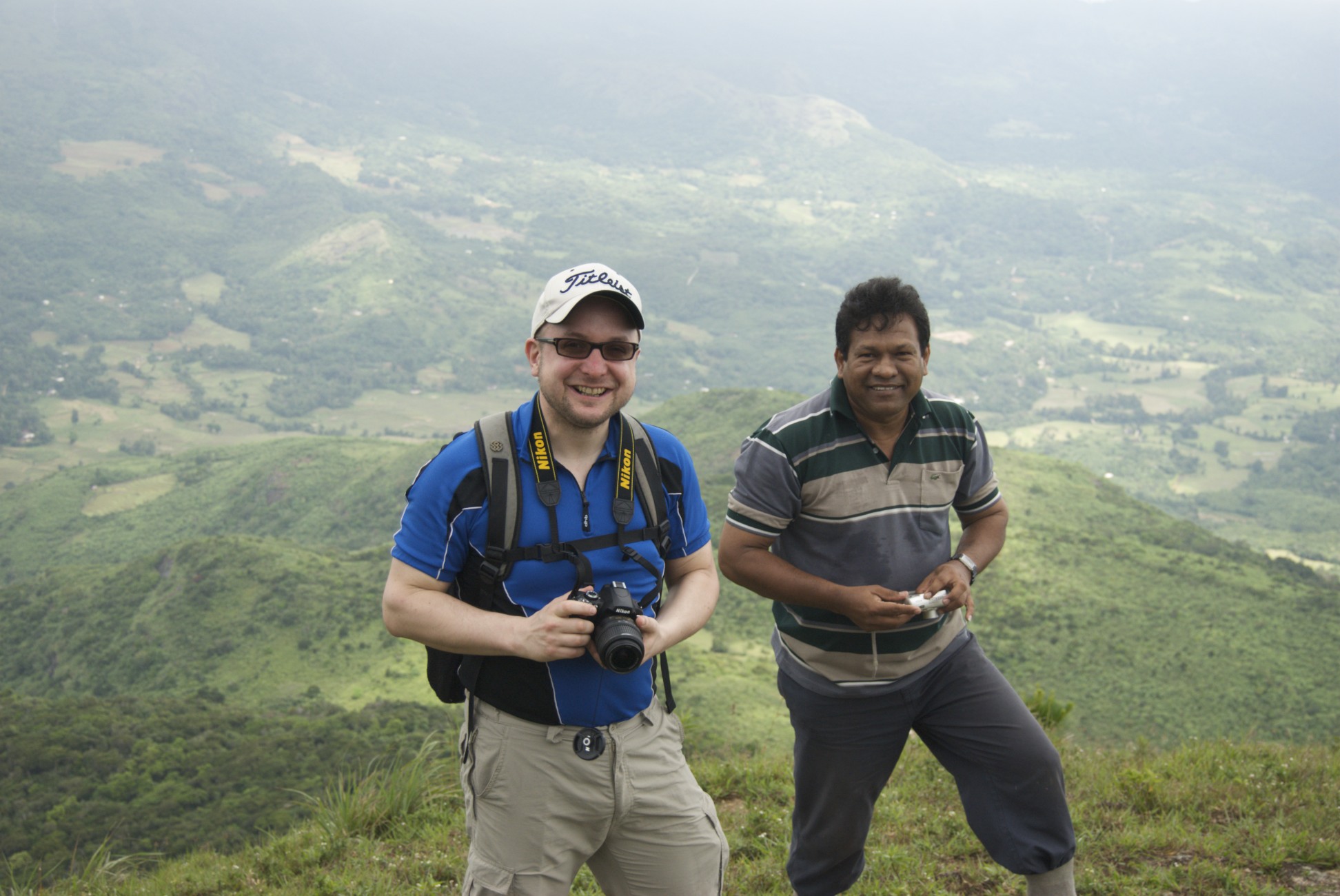 two men standing on top of a mountain taking pictures