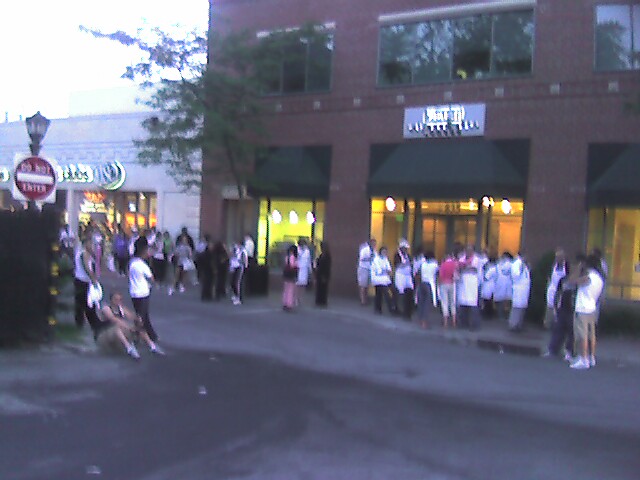 people are standing in front of an eatery and a mall