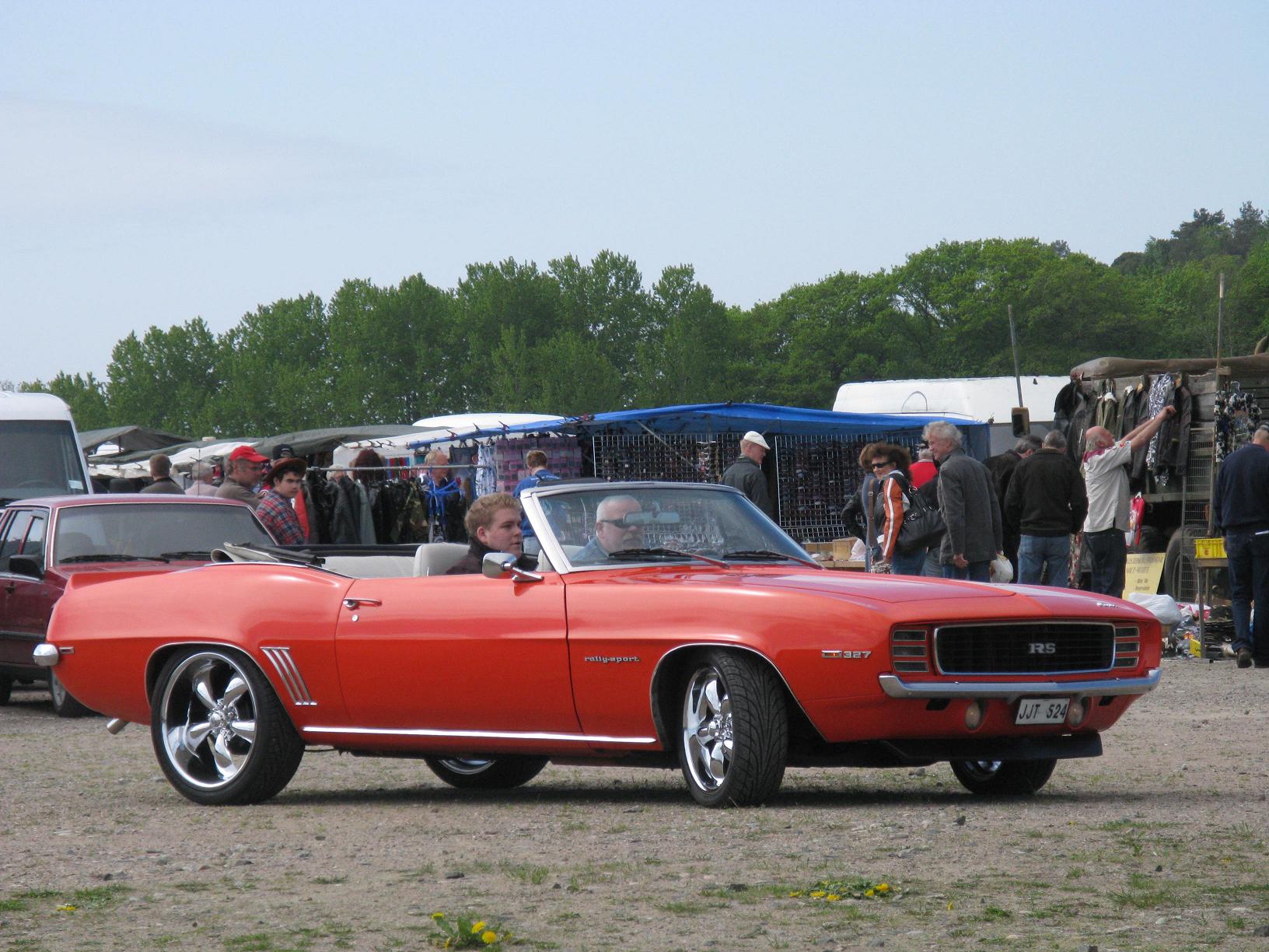 two red convertible cars are parked in a lot