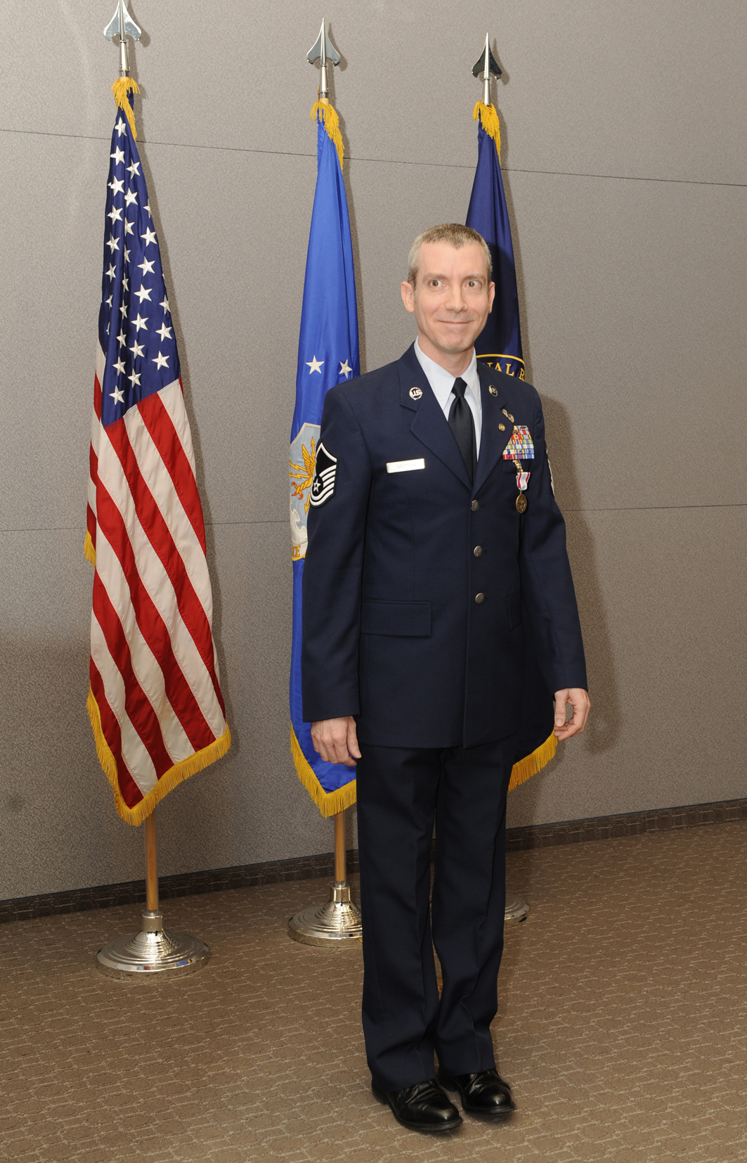 an air force officer standing in front of two american flags