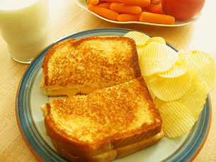 two slices of grilled bread with er, orange slices and carrots beside a glass of milk