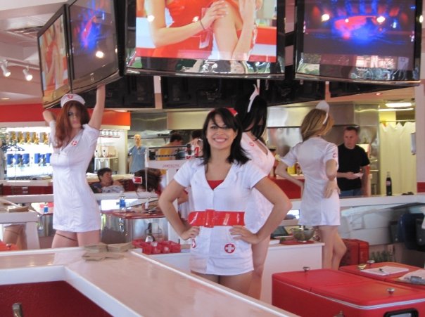 some women standing up in a restaurant holding up tv screens