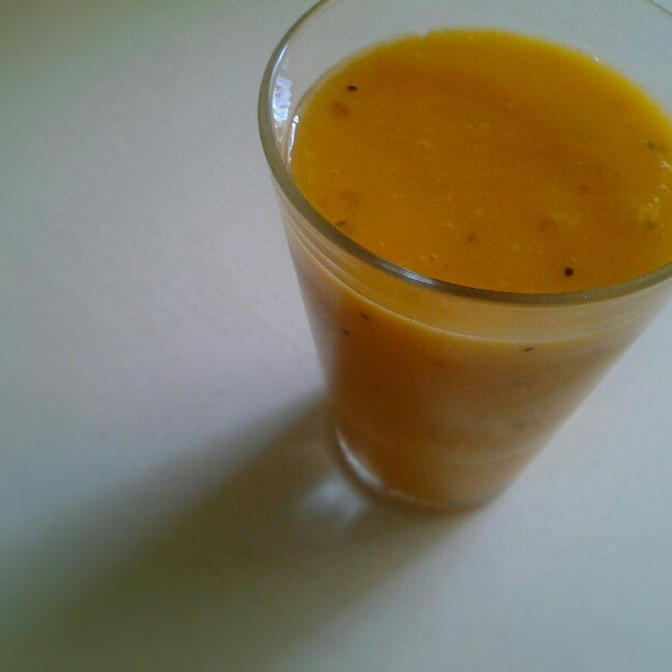 a glass of liquid with an orange substance in it