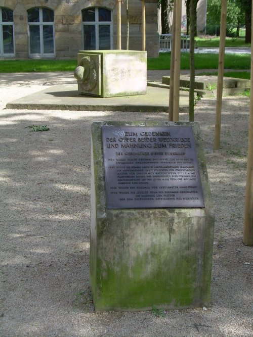 a monument with a list on it in front of some trees