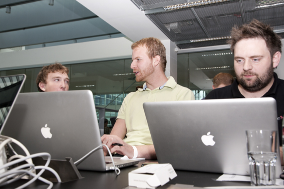 three men working on laptops in an office
